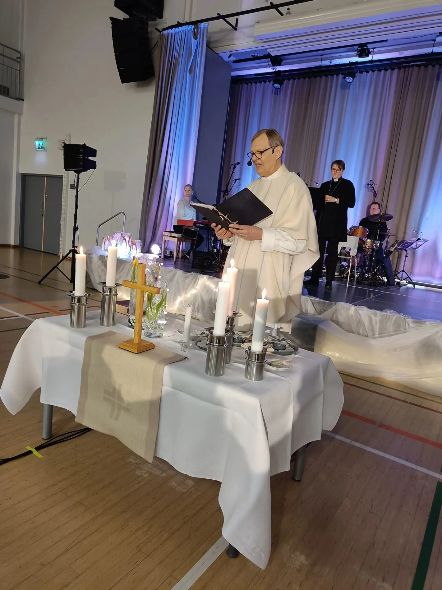 A person in a white robe reading a book on a table with candles and a cross

AI-generated content may be incorrect.